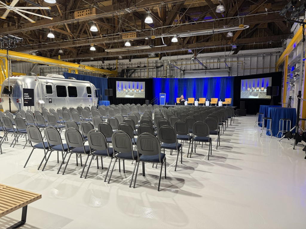 ATCO town hall set in an aircraft hangar with stage, LED screens and blue drape